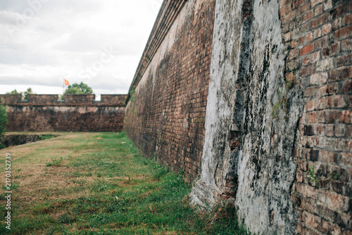 Canvastavla Historic brick fortress wall and Vietnamese flag in a grassy courtyard