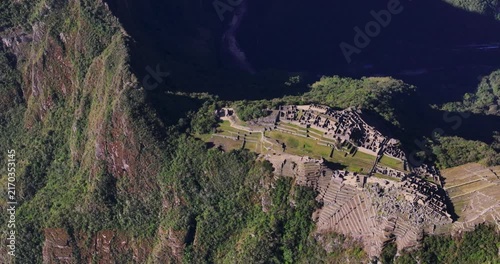 Aerial view of the ancient Incan ruins of the Historic Sanctuary of Machu Picchu nestled in the Andes mountains with green terraces and stone structures in Peru