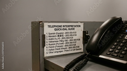 Nurse Using a Telephone Interpretation Service with a Dual-Handset Phone at a Patient Bedside