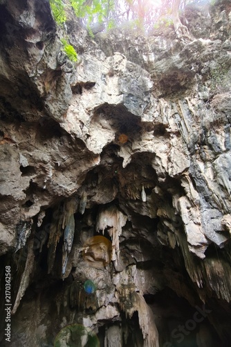 Low angle view of a dark cave exit with sunlight streaming into the cave shaft.