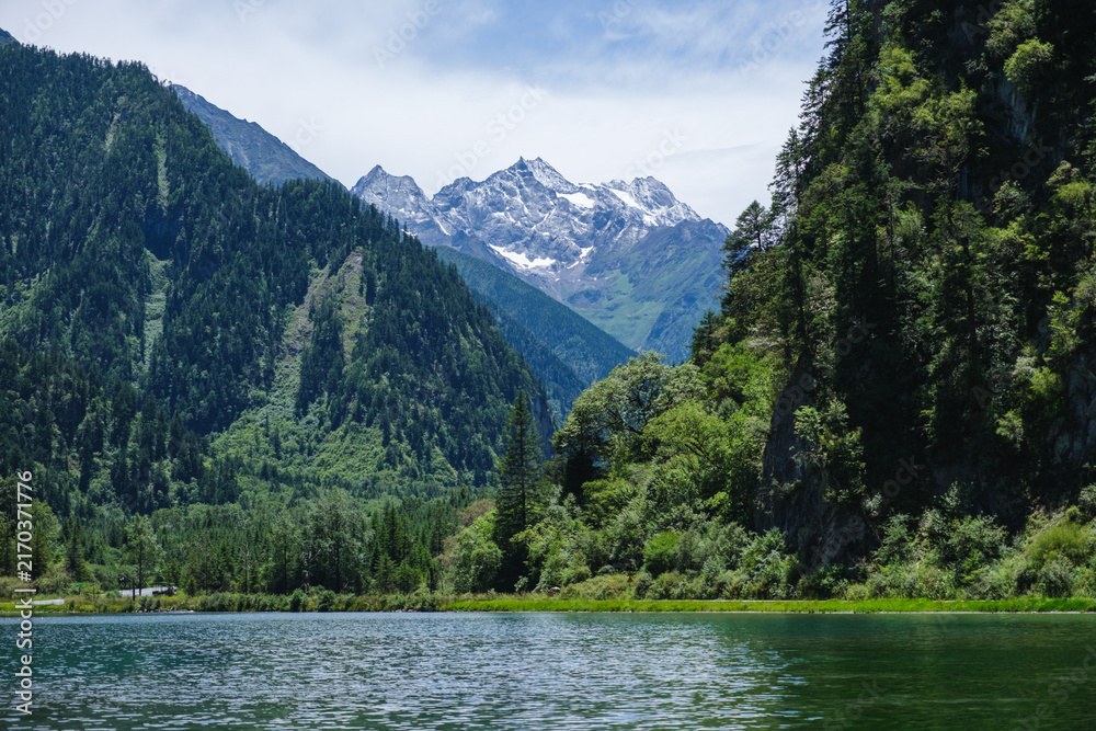 Naklejka premium Landscape of the lake and greenery forest with four girls mountain range in Bipenggou, Chengdu China