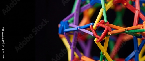 Colorful hoberman sphere toy, an expandable geometric structure, sits against a plain black background.