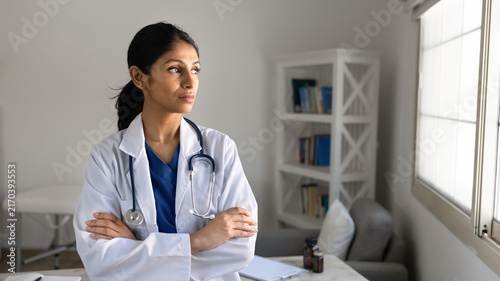 Photography Serious South Asian female doctor in uniform posing with arms crossed for medica