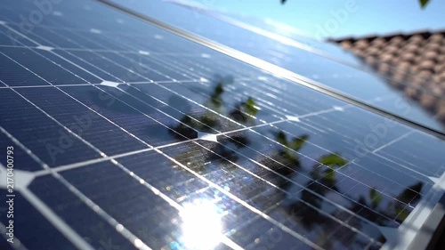 Close up of solar panels with sun reflection and roof tiles in background showcasing renewable energy technology
