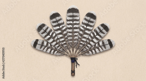 Traditional native style feather fan made of striped turkey feathers on beige background