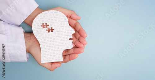 Fotografie Caring hand holding paper head puzzle with missing brain piece shows hope for he