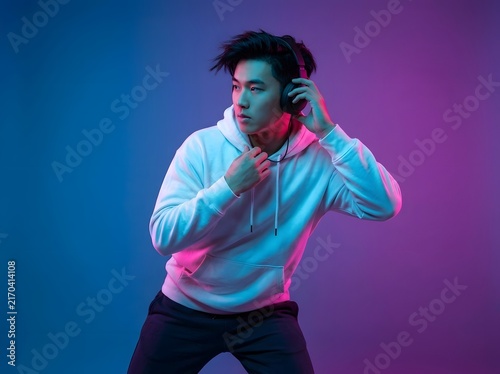 Young asian man wearing headphones under blue and purple neon light