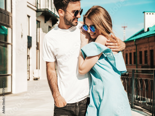 Portrait of smiling beautiful woman and her handsome boyfriend. Woman in casual summer jeans dress. Happy cheerful family. Female having fun. Couple posing on the street background in sunglasses