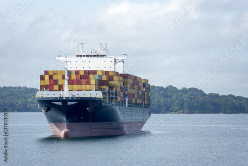 A giant container ship crosses Gatun Lake on the Panama Canal route, highlighting the impressive scale of modern commercial vessels navigating the tropical waterway.