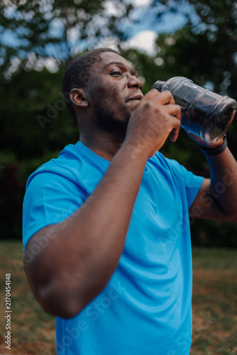 Obraz w ramie Black man hydrating outdoors after workout