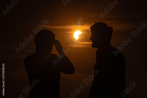 Partial solar eclipse with moon obscuring glowing sun and dramatic sky