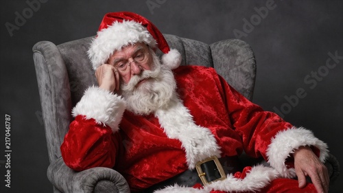 Elderly man in red Santa suit sitting in armchair with thoughtful expression, with santa, santaclaus, elderly, older detail