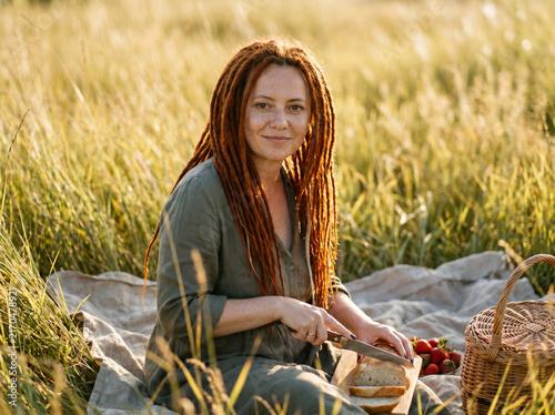 Woman picnic in a field slicing bread from a basket on a blanket for natural lifestyle wellness background and countryside banner