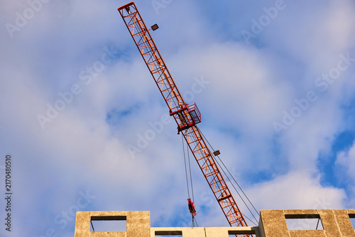 Orange tower crane jib with trolley and pulleys in action