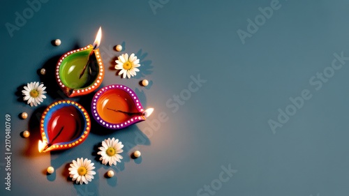 Happy Diwali Three decorative colorful clay diyas with white daisies and pearls on a blue background for a minimalist Diwali aesthetic