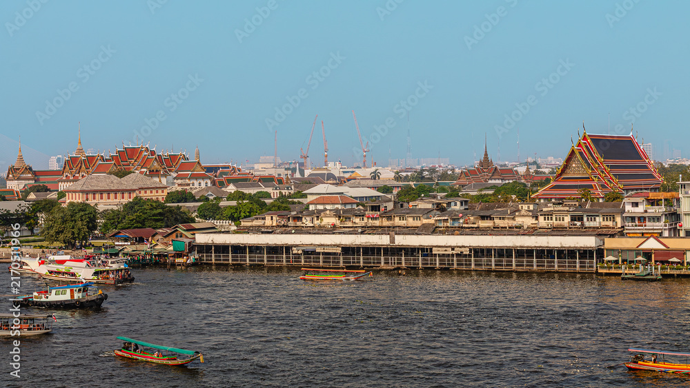 Obraz premium Cityscape view of riverside temples and boats during daytime in Bangkok, Thailand