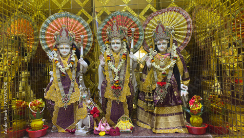 Obraz na płótnie Gilded altar with three ornate statues of Hindu deities adorned with garlands and umbrellas