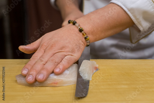 Foto A sushi chef slicing a raw fish to prepare for a traditional omakase meal inside