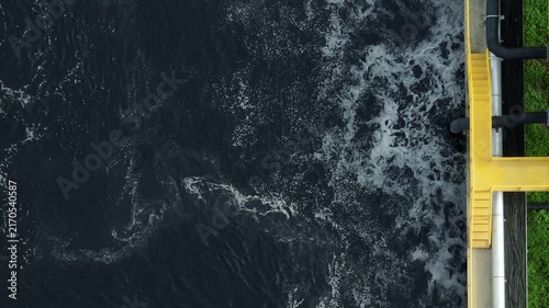 Aerial close up of dark wastewater in a factory treatment tank with foamy oxygenation, illustrating industrial water recovery, clean technology, and sustainable resource conservation. 4k.
