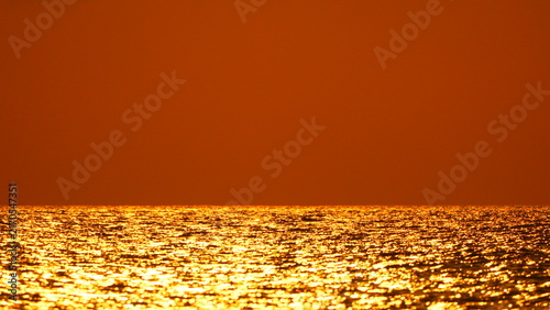 Фотография Sunset ocean water shimmering golden waves at sea under a vast orange sky with p