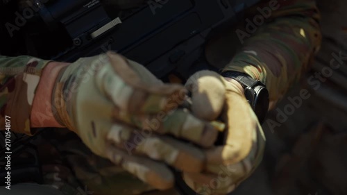 Macro close-up of soldier's hands in camouflage tactical gloves carefully loading bullets into rifle magazine on dark surface. Military warfare detail concept for defense, armed forces and editorial u