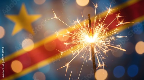 Burning sparkler with flying sparks against blurred Democratic Republic of Congo flag background with bokeh lighting