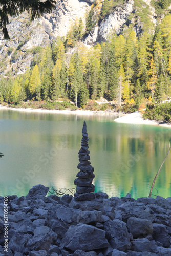 Lake Braies (Pragser Wildsee) in the Dolomites, Italy, with turquoise alpine water, forest reflections and a peaceful stone sculpture on the lakeshore. Scenic mountain landscape and nature destination