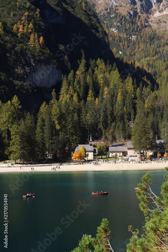 Lake Braies in the Dolomites, Italy, surrounded by alpine forests and mountains. Calm dark turquoise water with traditional wooden boats and a peaceful lakeside landscape.