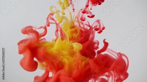 close-up shot of vibrant red and yellow acrylic ink dispersing in clear water. T