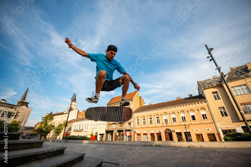 Obraz na plátně Skateboarder performing a kickflip trick in an urban square