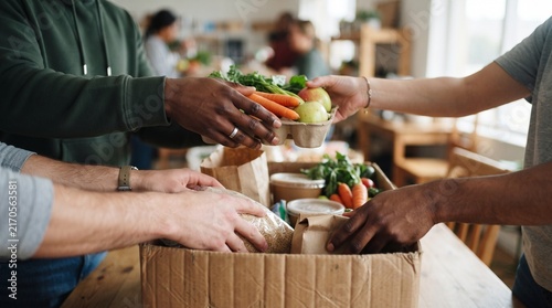 Close-up of diverse volunteer hands placing fresh food packages into a donation box, featuring natural textures, soft window light and shallow depth of field for a compassionate humanitarian concept.