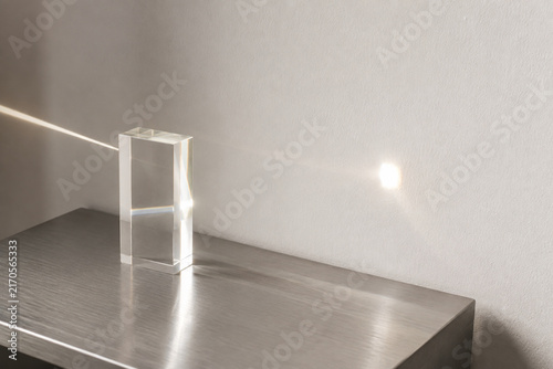 Sunbeam passing through clear acrylic block onto white wall, light transmittance concept