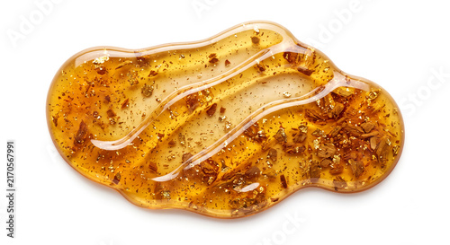 Macro shot of golden amber resin oil swatch with gold flakes and cedarwood texture
