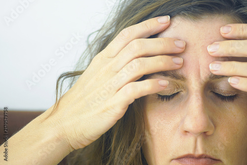 Extreme close-up of woman gently massaging forehead acupressure points with fingertips. Captures targeted self-massage technique, facial muscle tension relief, and natural headache point stimulation.