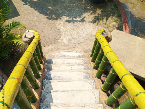 Concrete staircase with vibrant bamboo inspired handrail providing access to lower ground outdoors in sunny weather