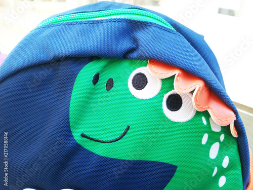 Children's dinosaur backpack displaying a playful green creature for school or travel adventures