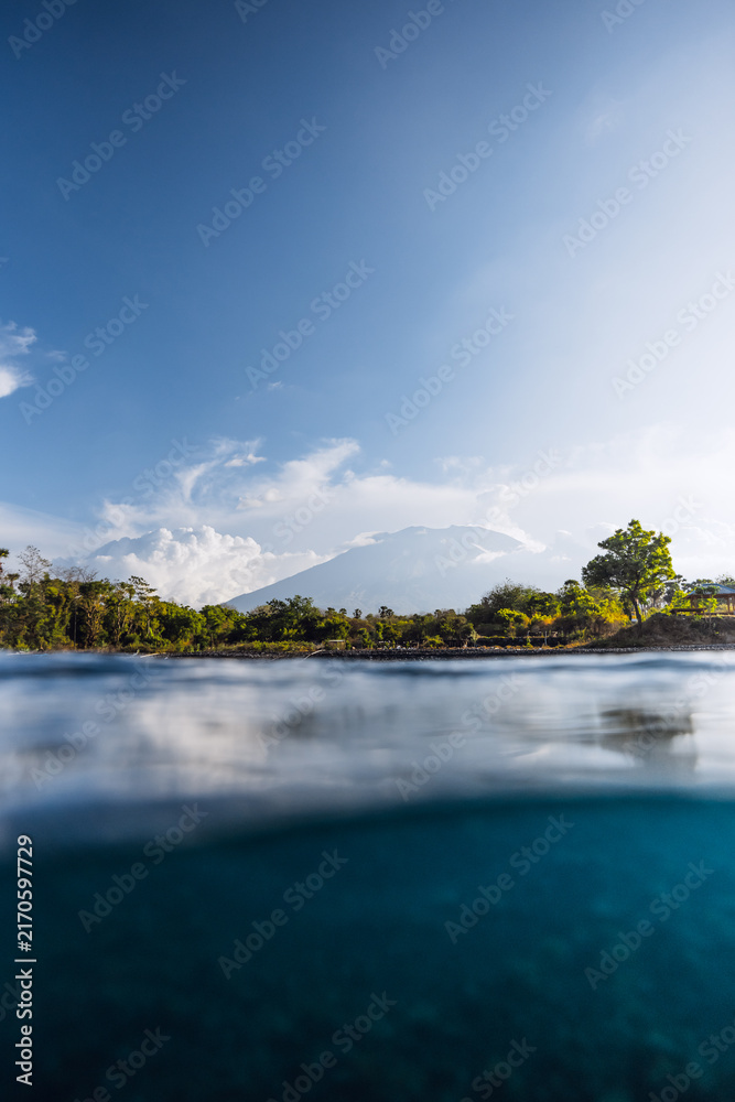 Naklejka premium Blue ocean and volcano mountain in Bali. Split view of blue sea waters surface