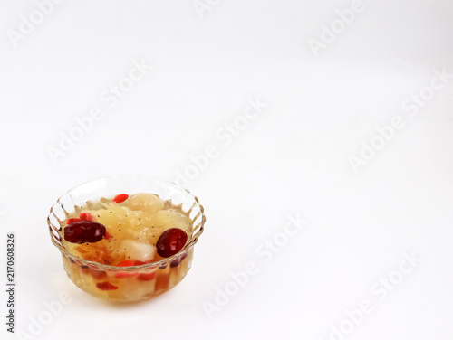 A studio shot of a traditional Asian sweet dessert soup served in a clear glass bowl. The healthy nourishing soup is ideal for health, wellness, and culinary themes.