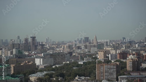 Elevated panoramic city skyline with dense midrise foreground, construction cranes, and distant high-rise cluster under pale blue sky, with city, skyline urban, building detail