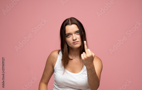 Bild auf Leinwand Young woman showing rude middle finger gesture expressing anger, defiance, and d