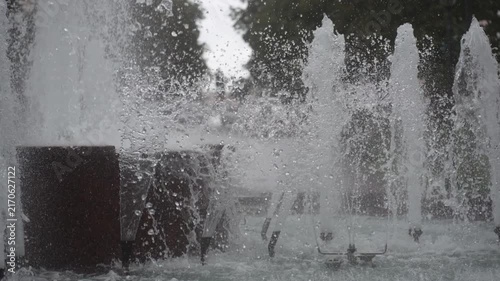 Close-up urban fountain jets ejecting water into vertical columns and dense spray at basin level with overcast diffuse light and rhythmic composition, with water,fountain, jet, splash detail