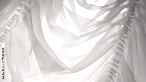 Layered sheer white fabric draping and gathered ruffle backlit by strong diffuse light,with fabric, sheer, translucent, white detail, showing chiffon, texture, fold, drape context