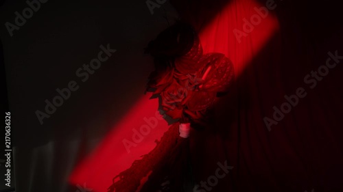 Moody close-up of rose bouquet illuminated by sweeping red spotlight across draped fabric, with rose, bouquet, spotlight, red detail, showing shadow, contrast, petal, fabric 