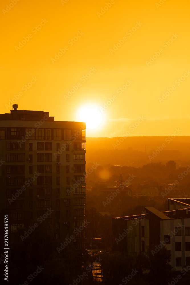 Naklejka premium A beautiful sunset and sunny rain. Orange and amber hues of a beautiful sunset against a backdrop of fog and light rain on a summer evening. Golden hour.