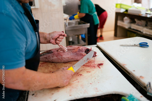 Fishmonger filleting fresh tuna fish in market