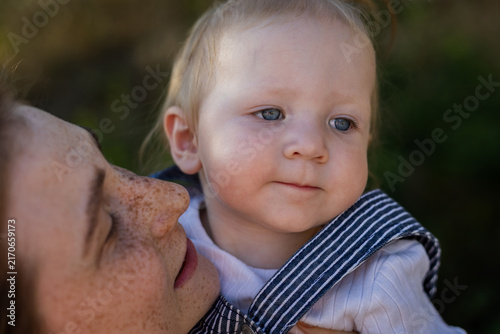Fotografía Mother's gentle touch, baby's curious gaze, a moment of pure connection outdoors