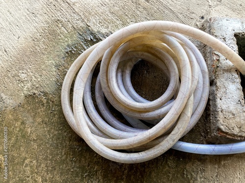 coiled water hose resting on a concrete floor