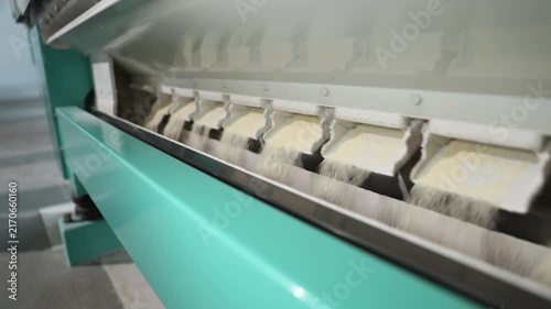 Automated industrial machine sieving and processing wheat flour in a modern mill factory, showing the production line and grain sifting process for making food products