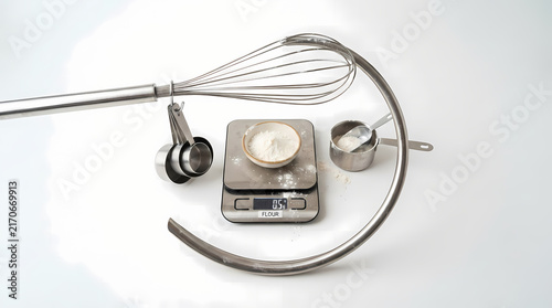 Kitchen whisk wrapping around digital scale and baking items