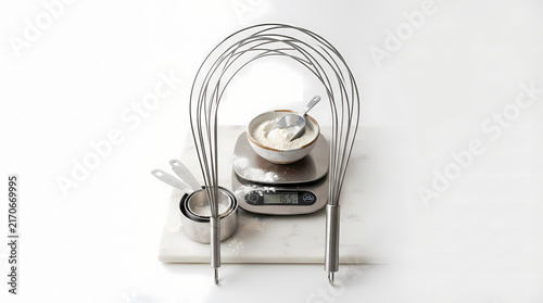 Flour bowl and digital scale framed under stainless steel whisk